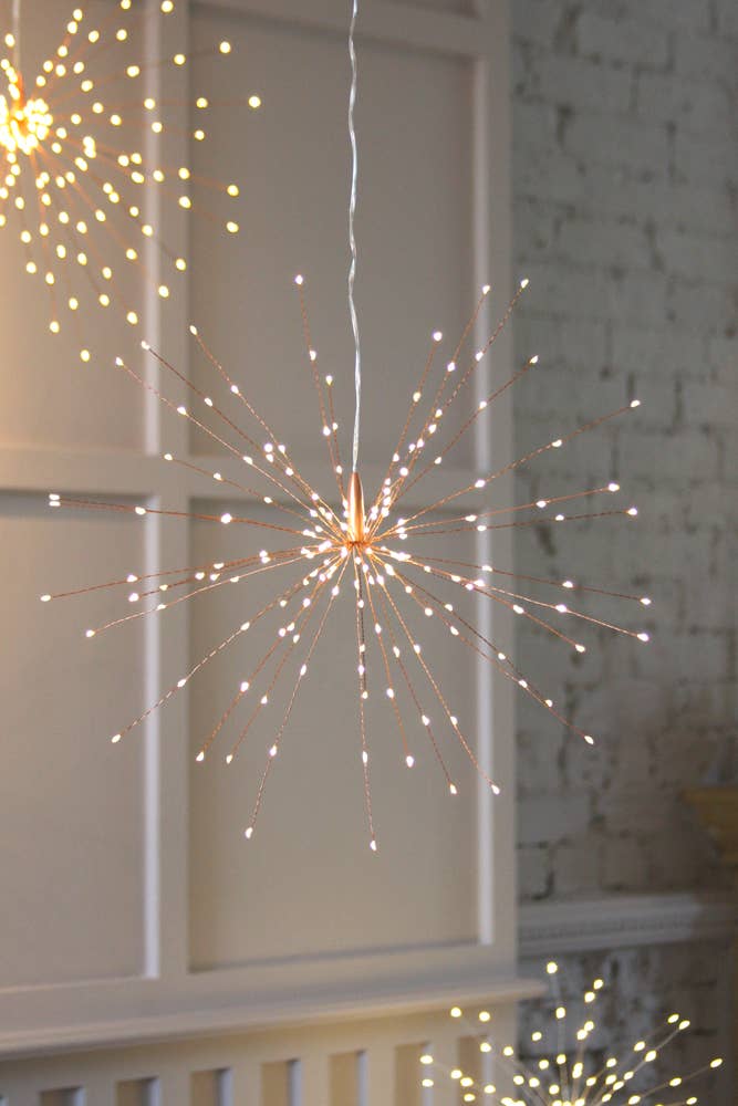Hanging Starburst LED in front of white wall and window. A cluster of three are lit with the central startburst in focus.
Copper hanging starburst 30cm great for indoors or outdoors.