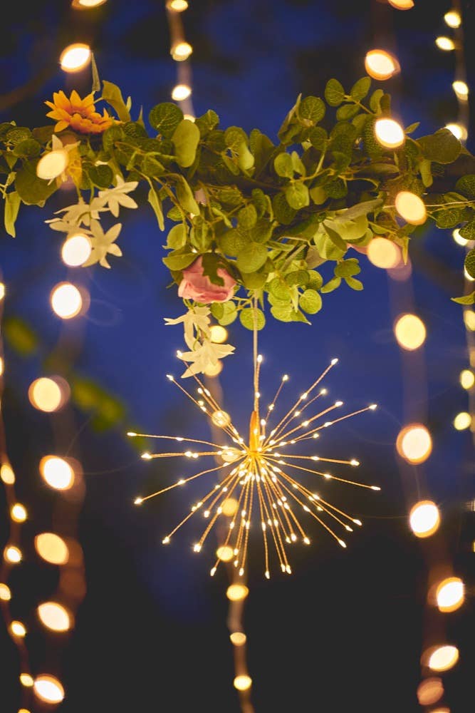 Lots of fairy lights and foliage against a dusky blue sky with a Hanging Starburst LED light covered in golden LED lights.