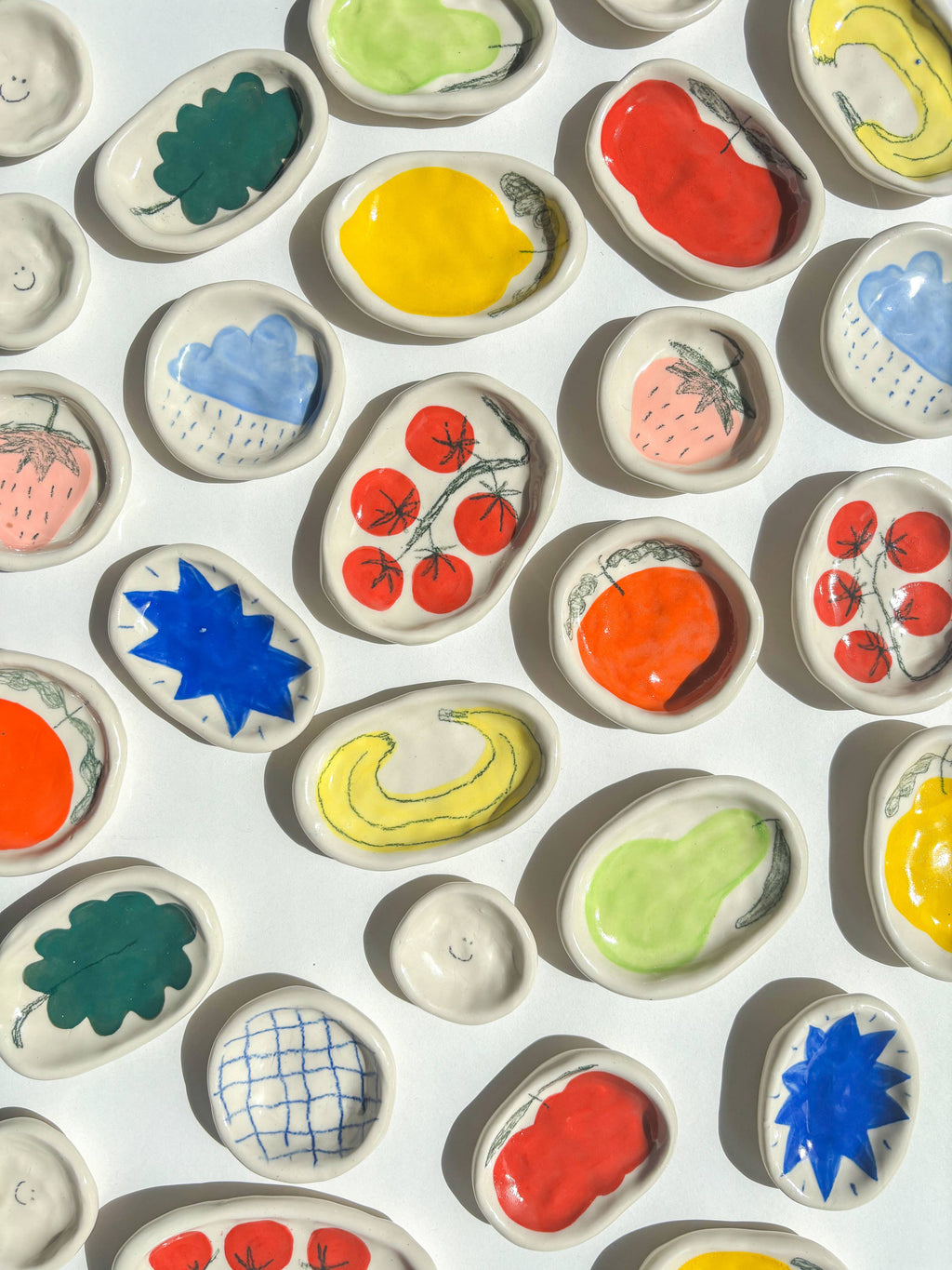 Assortment of colourful ceramic dishes with various designs on a white background. Handmade gifts.