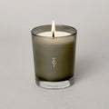Studio shot of lit candle - smoked glass holder has True Grace Logo on glass. Candle is white. Beautiful , luxurious gift.