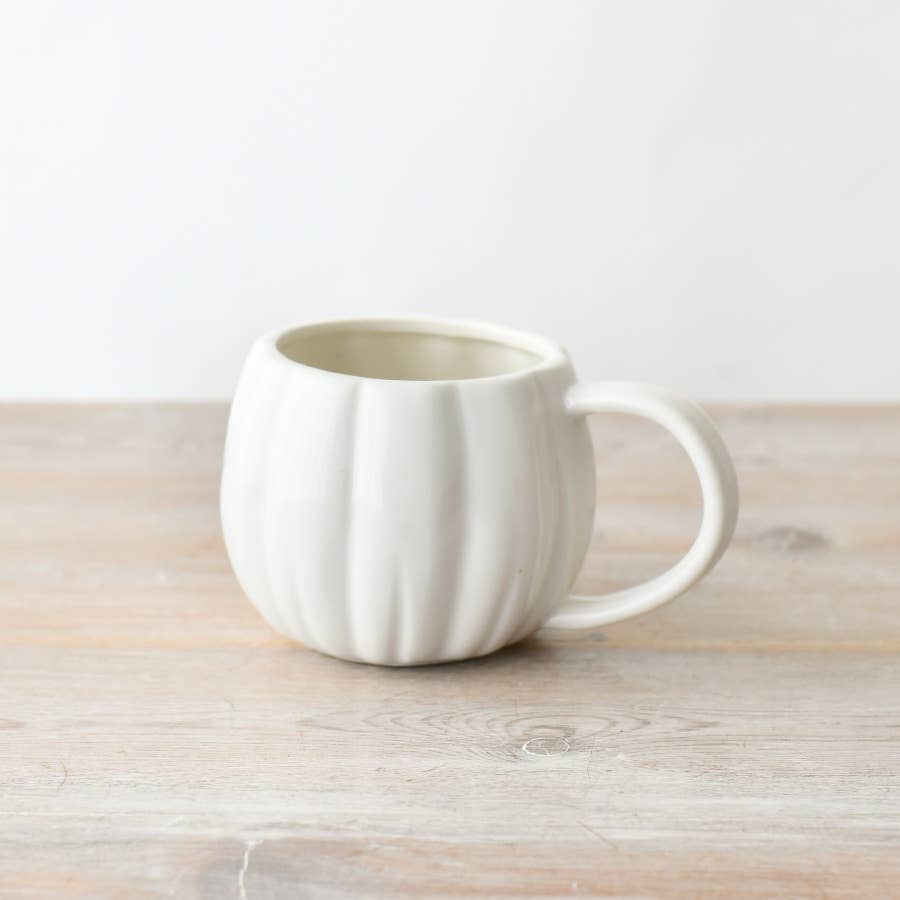 Pumpkin shaped mug on table with white background.