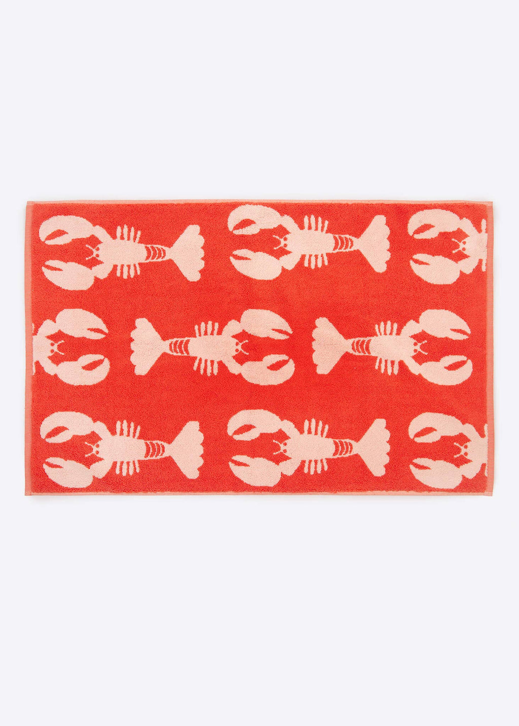 Coral towel with white lobster pattern on a white background