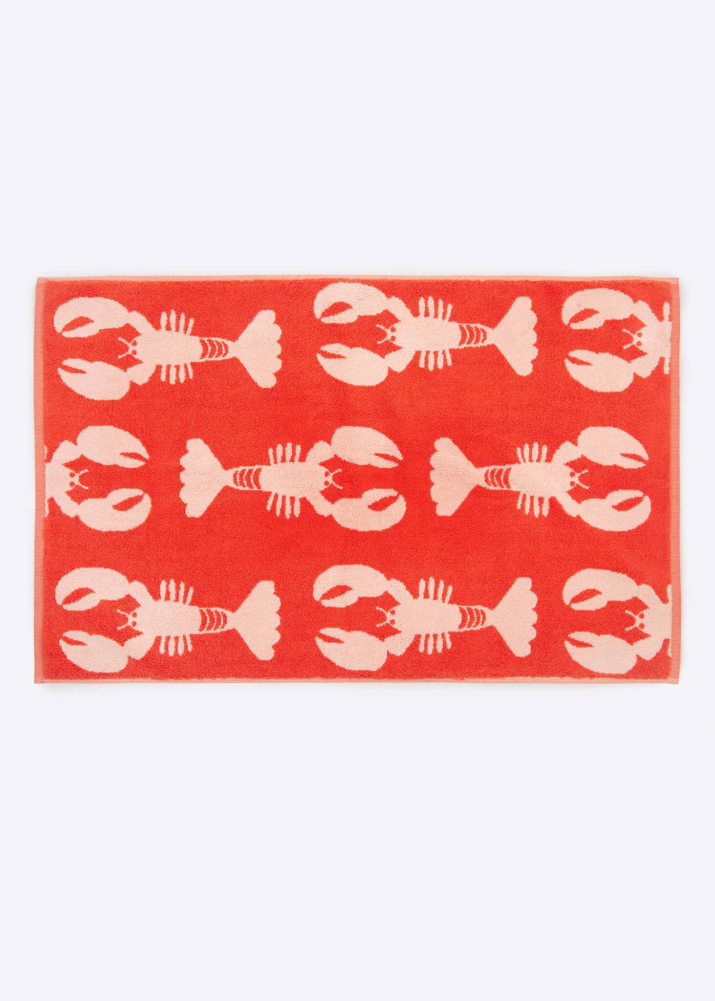 Coral towel with white lobster pattern on a white background