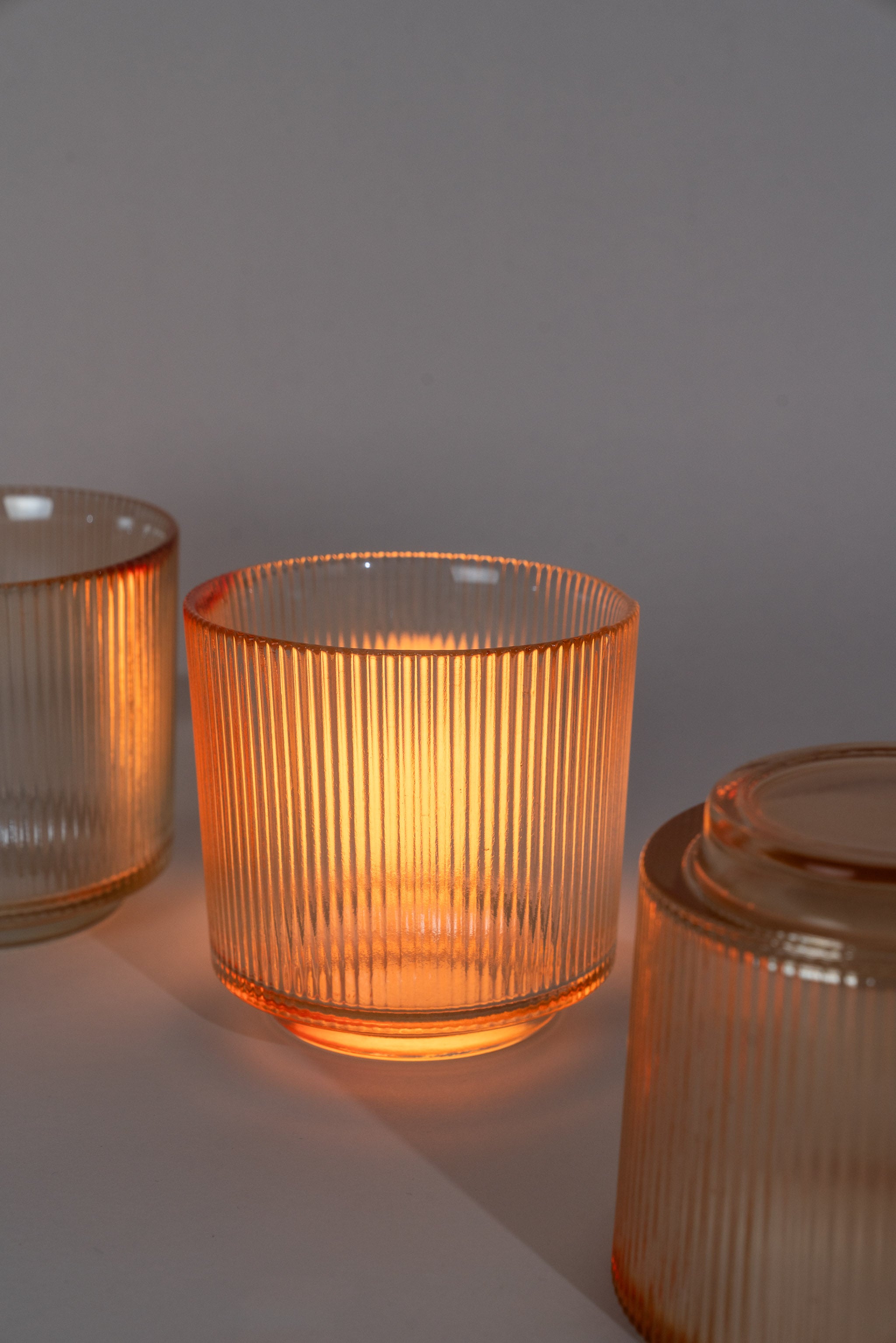 Amber glass holder backlit and glowing , one is purposefully upside down to show the shape of the base.
Glowing Amber Glass candle holder.