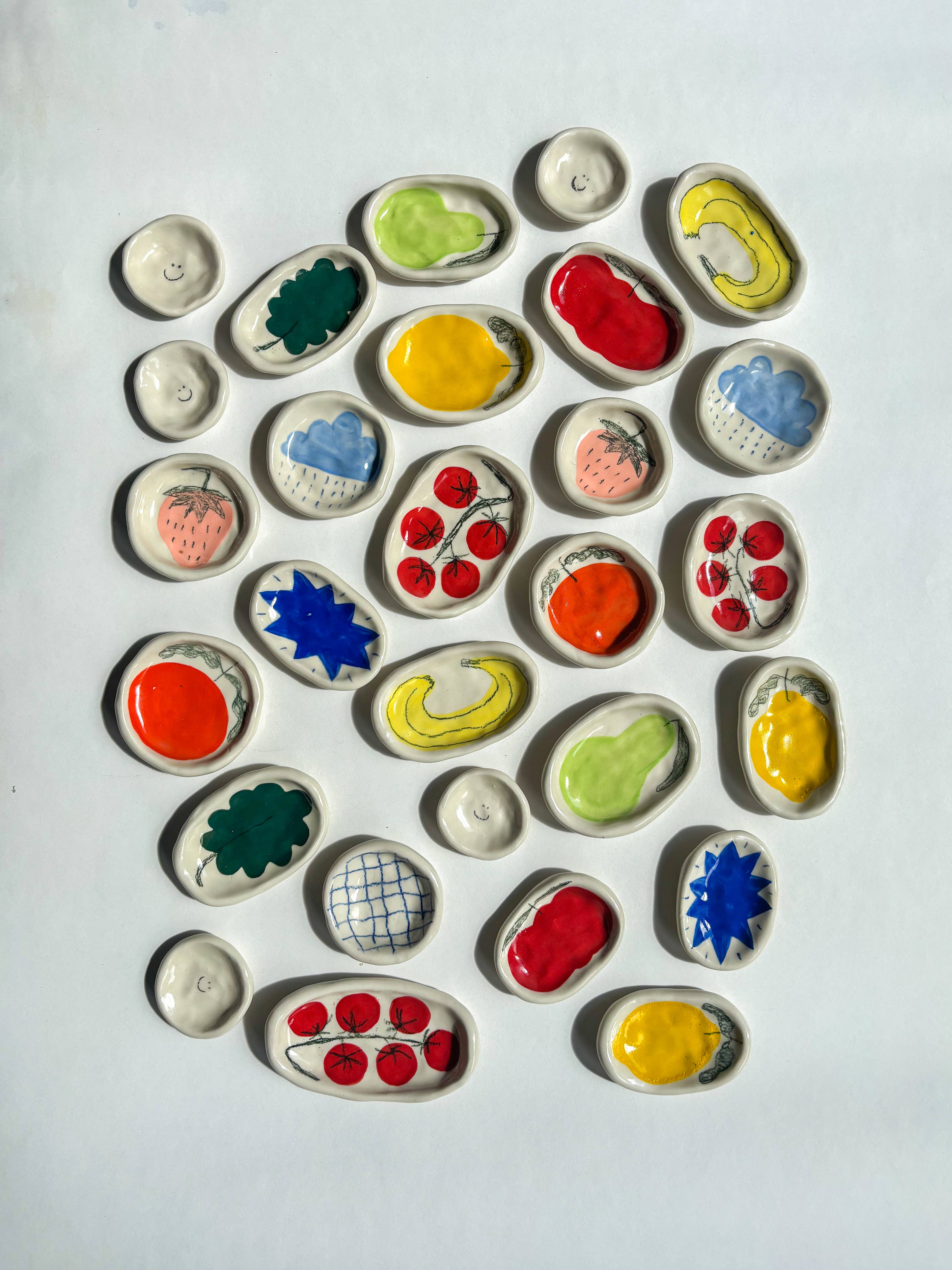 Assortment of colourful ceramic dishes with various designs on a white background. Handmade gifts.