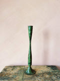 Medium Shelley verdigris candlestick showing green patina against pale pink wall. Candlestick on small rustic table top.