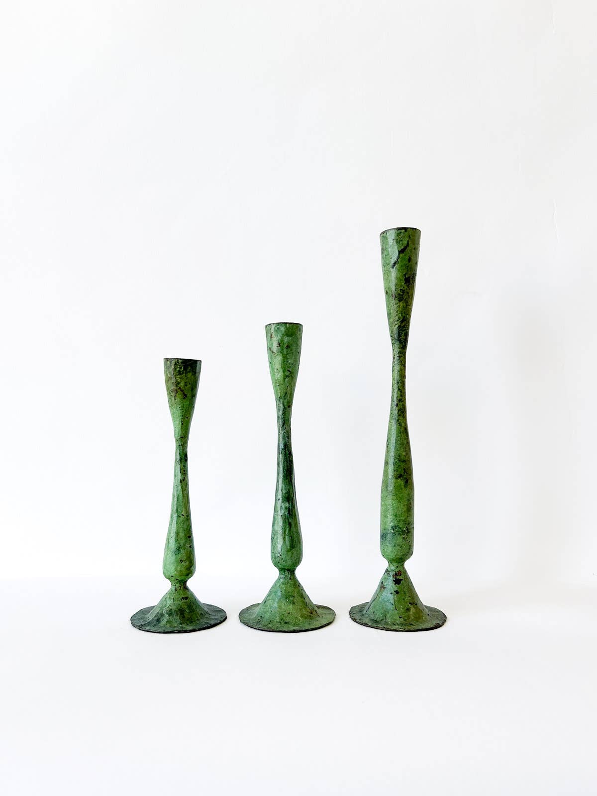 Studio shot on white backdrop showing family of three candlesticks in a line up, small, medium, large.
Hand forged Shelley candlesticks.