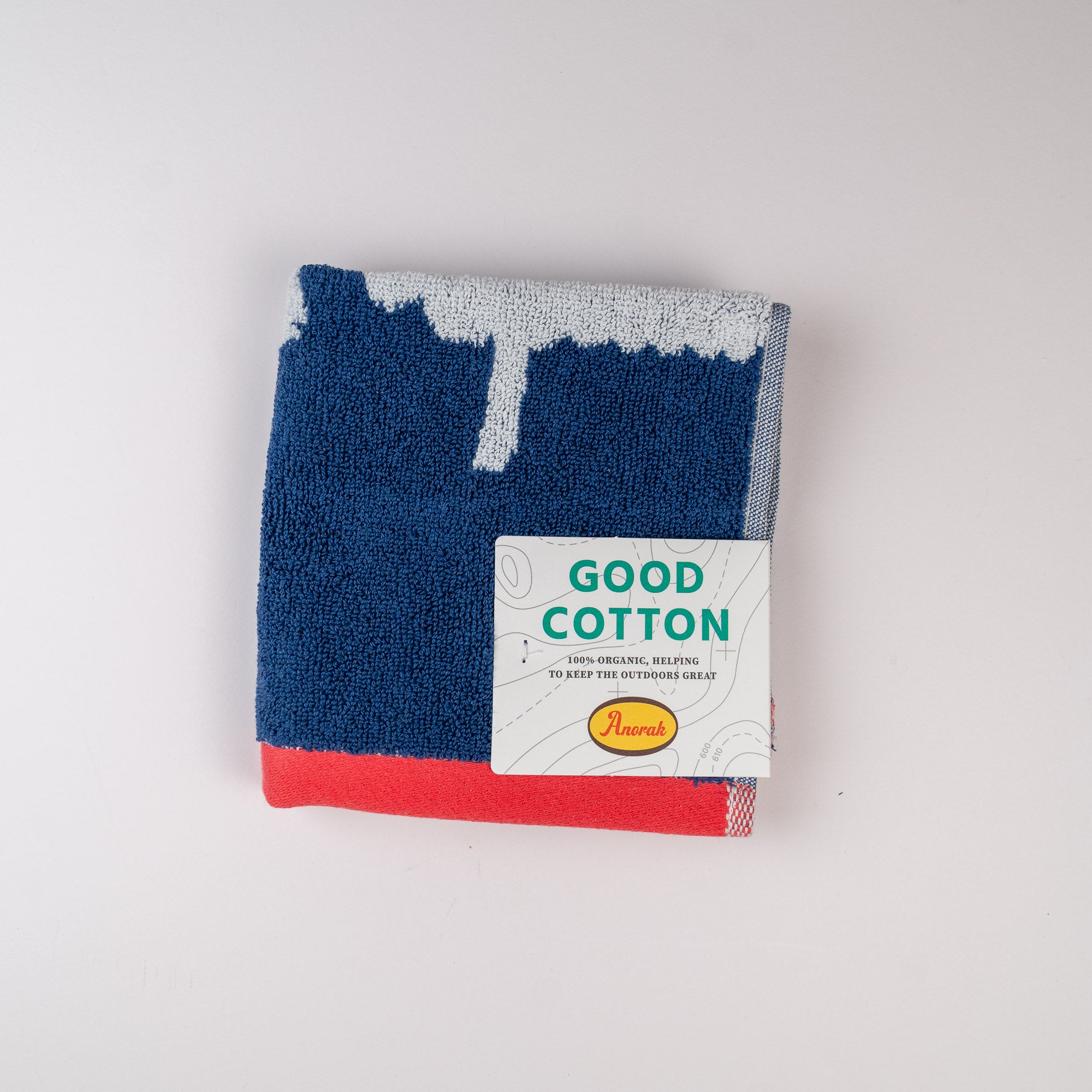 Folded blue and red towel with a Good Cotton label on a light gray background. Kissing sheep face cloth made by Anorak