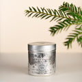 True Grace Village Christmas Tin Candle Number 39. Cream background with some pine foliage. Perfect Christmas Candle gift.