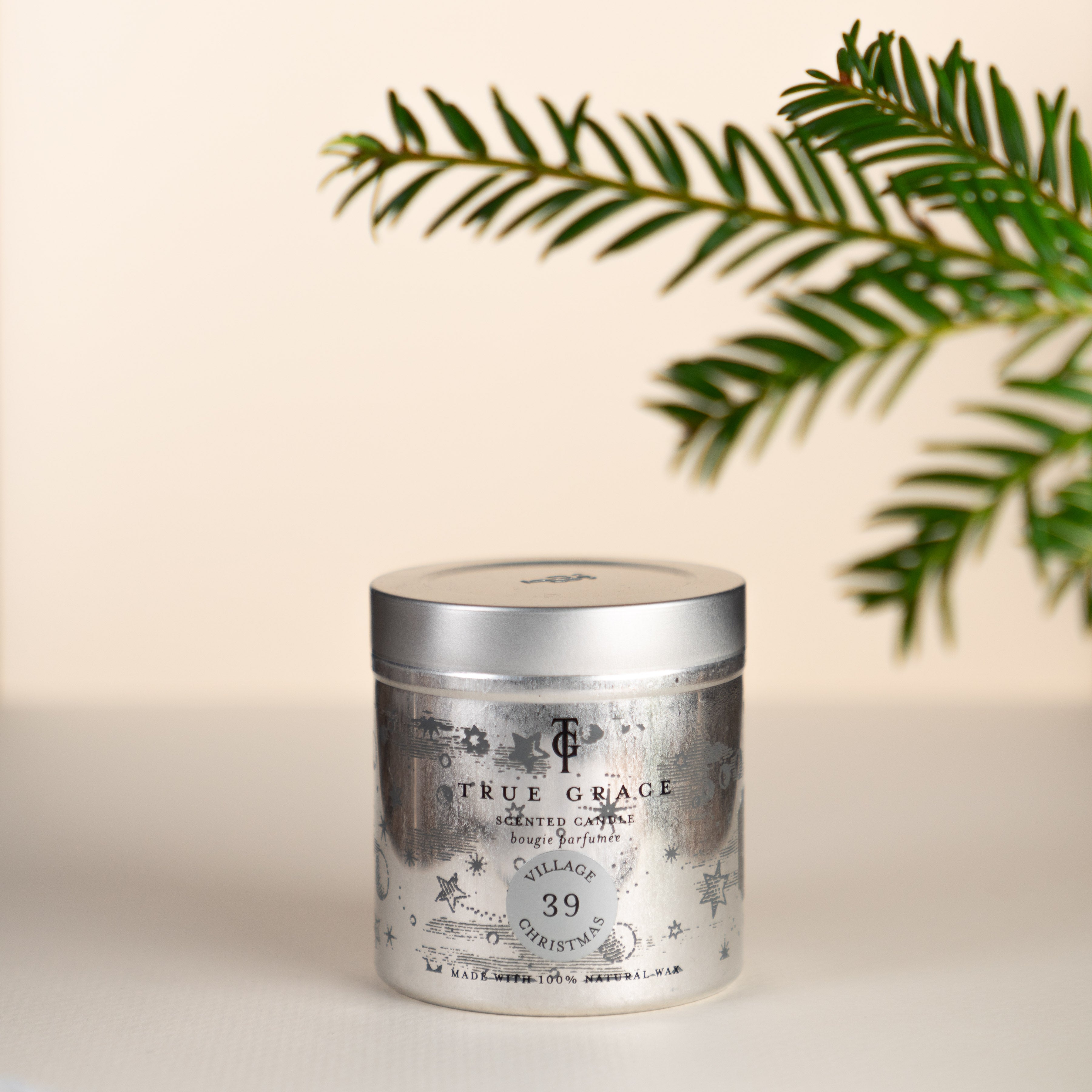 True Grace Village Christmas Tin Candle Number 39. Cream background with some pine foliage. Perfect Christmas Candle gift.