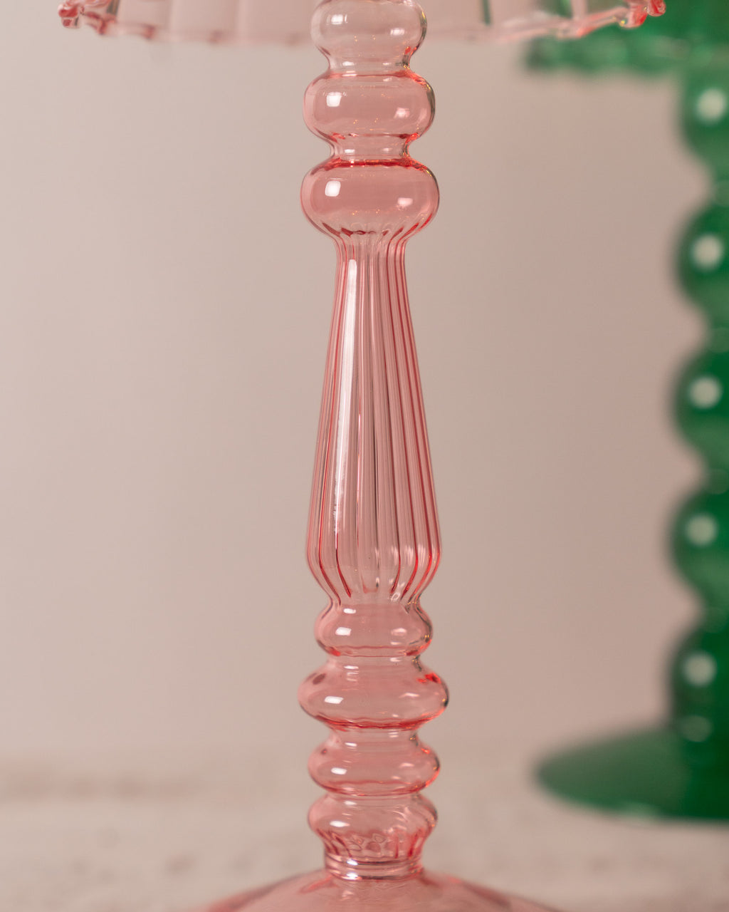 Close-up of a pink lamp-style glass tealight holder with a ribbed design on a light background.