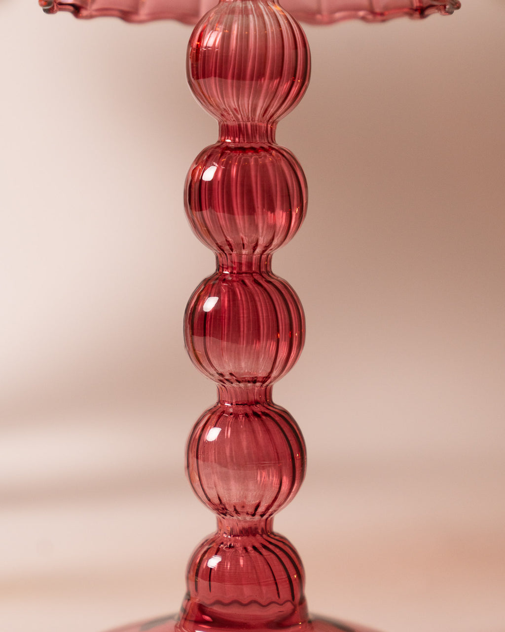 Close-up of dusky pink candle holder on a light pink background.