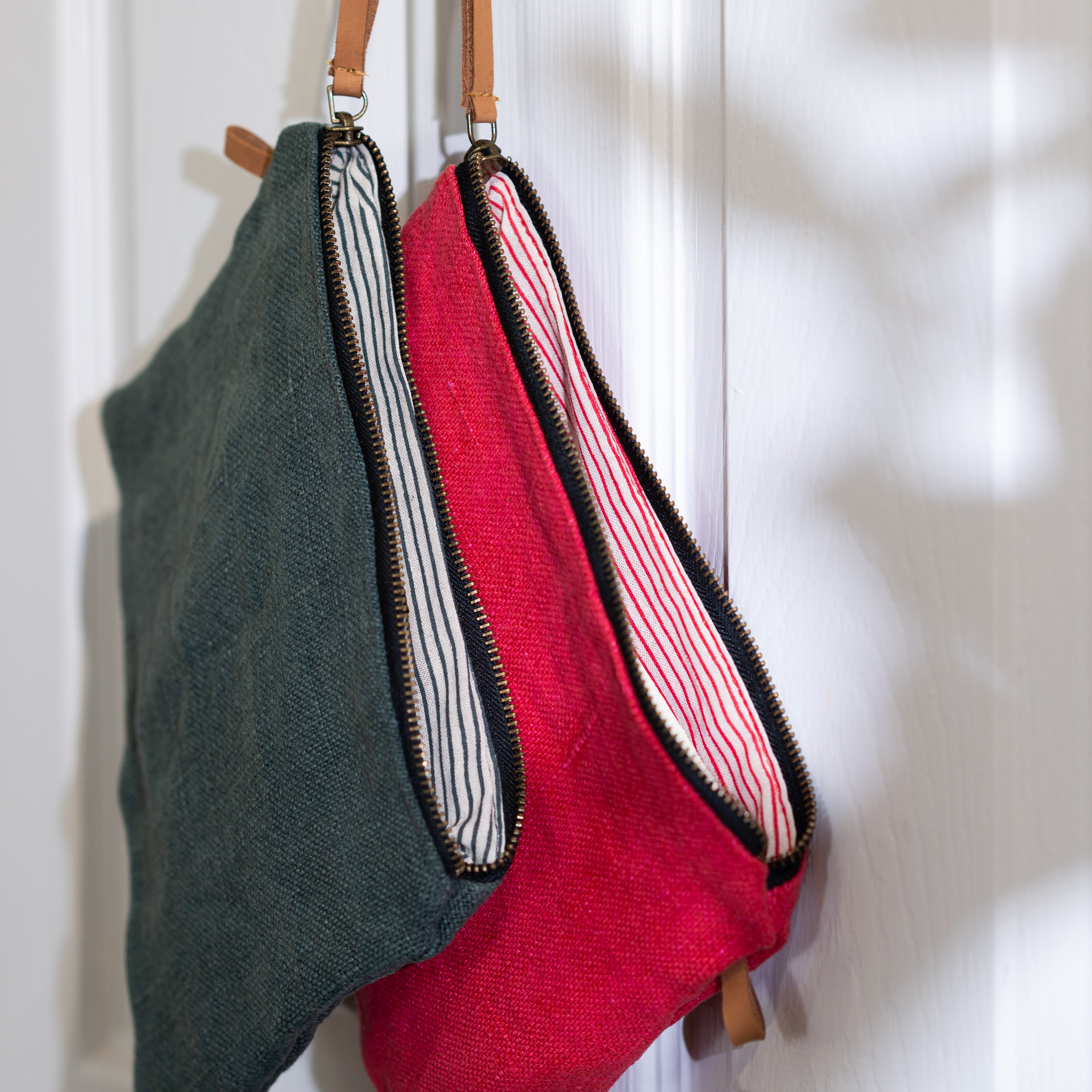 Grey and red bags hanging on door showing striped inner linings.