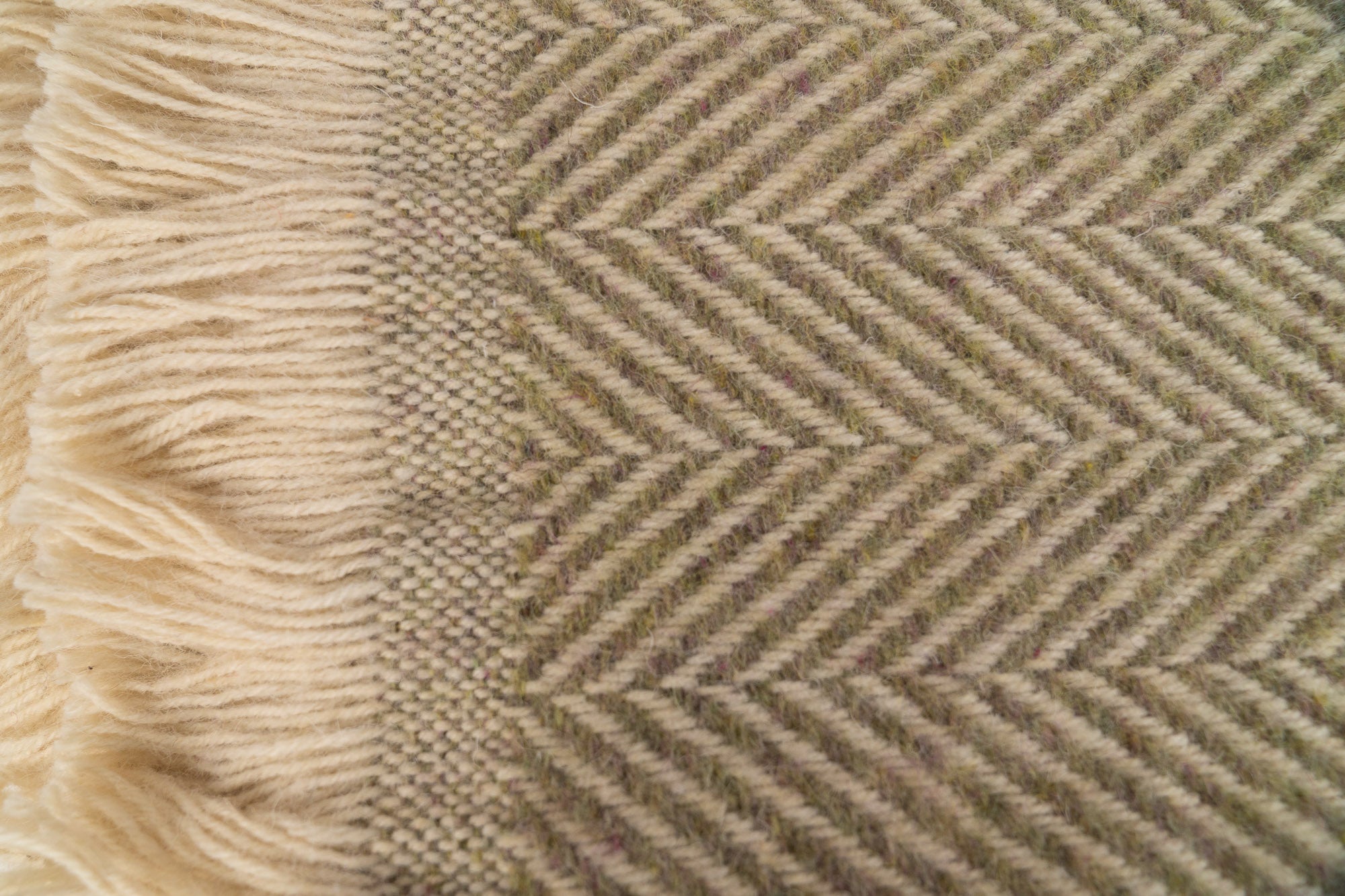 Close up of Tweedmill Textiles Pistachio blanket with cream firinge. 100% recycled wool