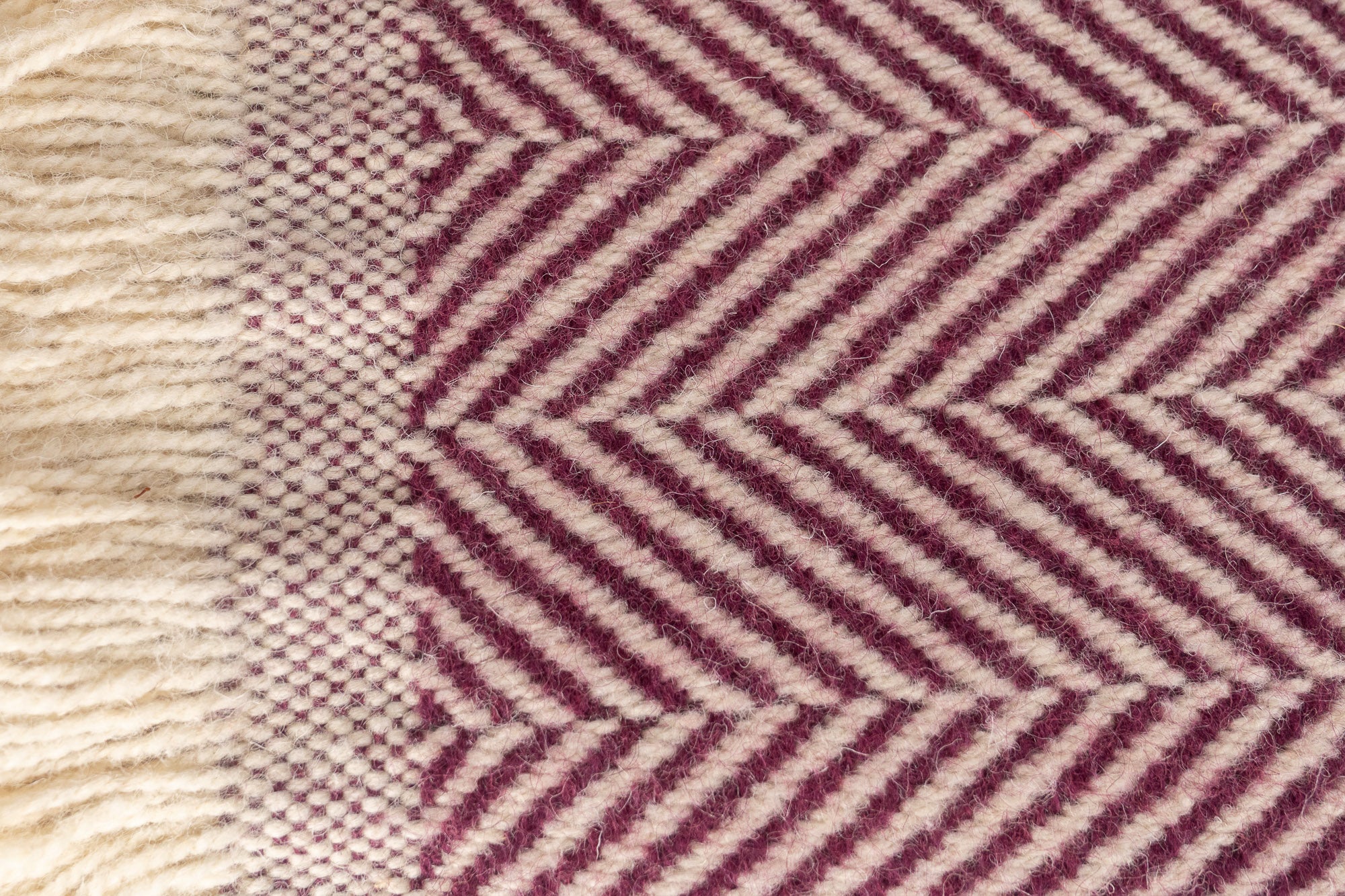 Close up of Tweedmill Textiles Plum blanket with cream firinge. 100% recycled wool.