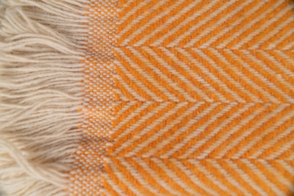 Close up of Tweedmill Textiles Mustard coloured blanket with cream firinge. 100% recycled wool.