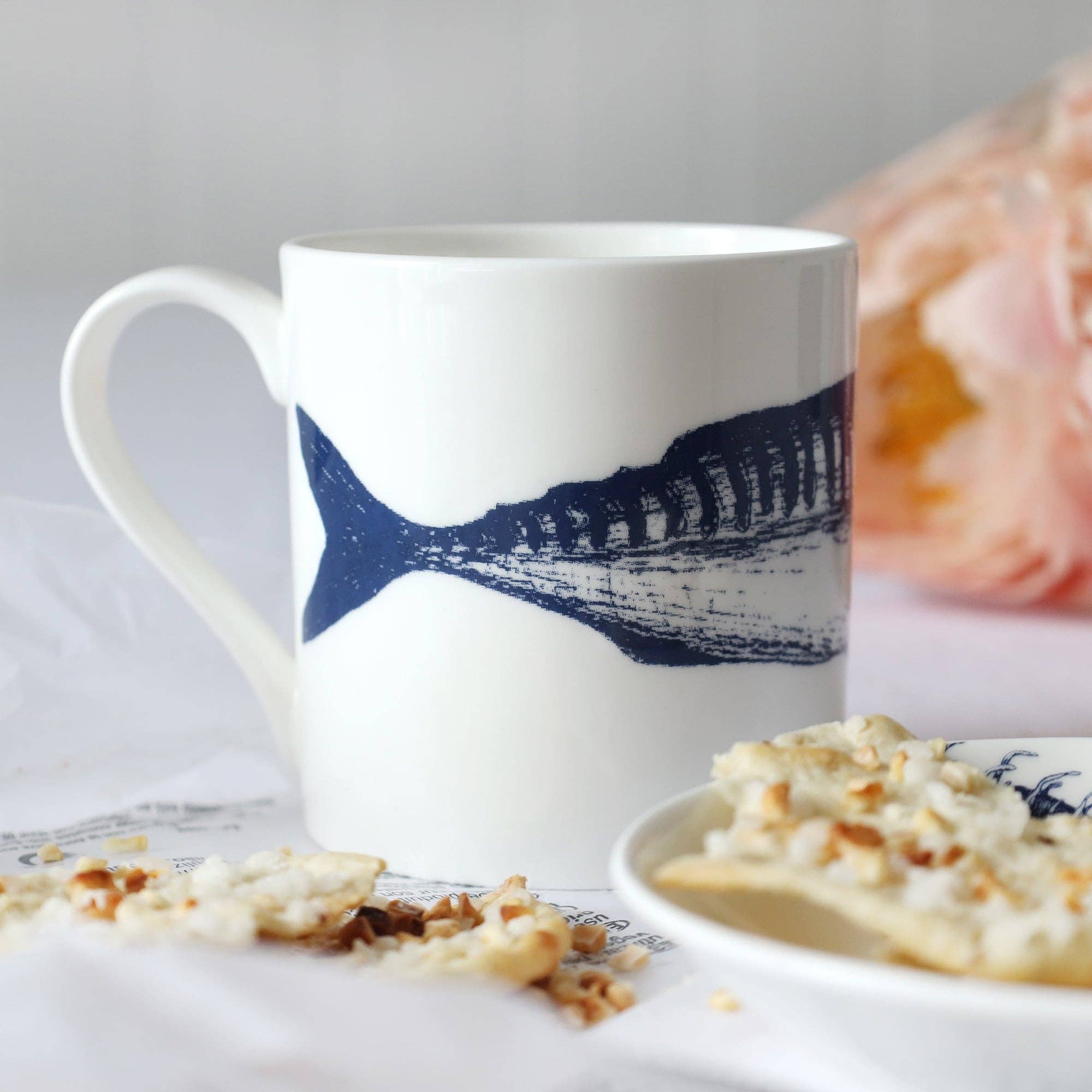 Close up of mug in breakfast setting - Illustration of fish tail in shot.