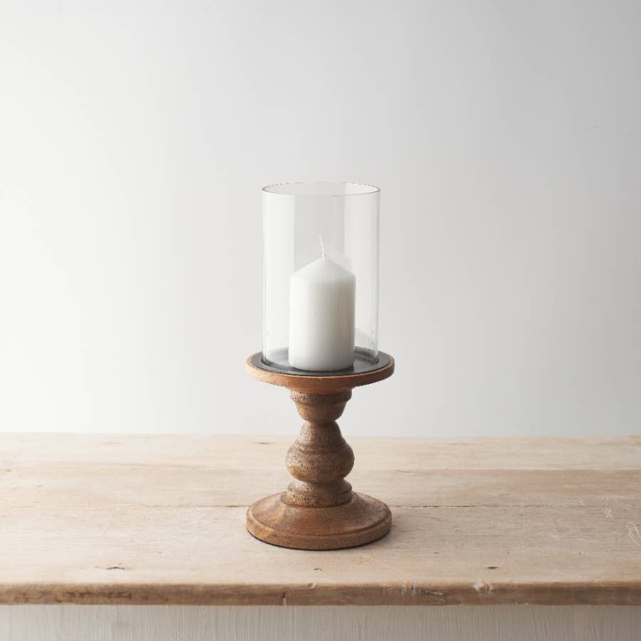 Wood and glass pillar candle holder with unlit cream candle, on white background.
