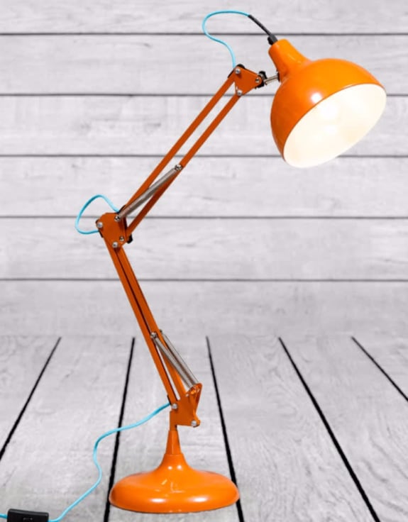 Orange desk lamp with a white light bulb on a wooden floor.